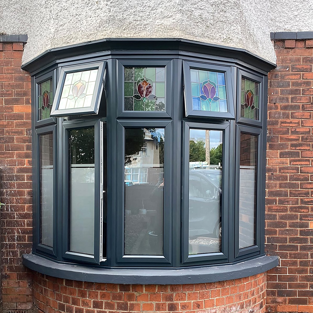 White UPVC bay window sprayed anthracite grey — drag to compare